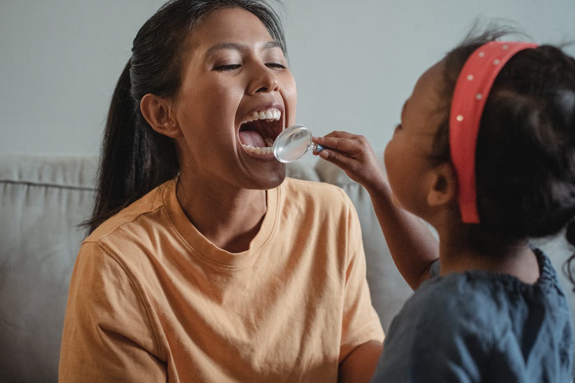 A photo showing a child holding a magnifying glass close to a woman’s face.