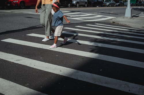 Crop mother and daughter crossing road