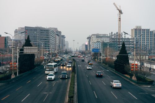 Free Busy urban street in Beijing with traffic, high-rise buildings, and cranes on a cloudy day. Stock Photo