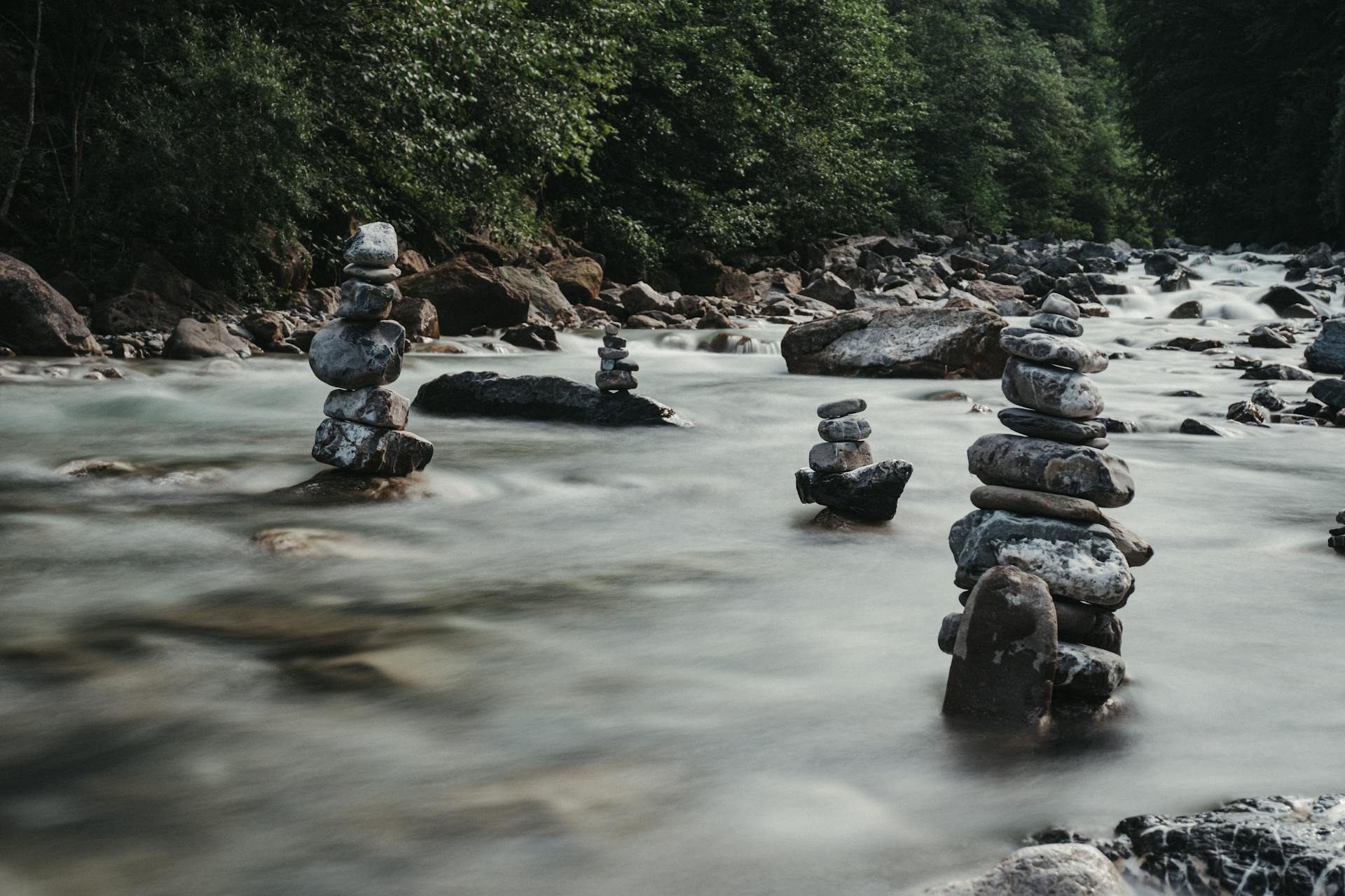 Picturesque scenery of rough zen rocks in wild river flowing through green forest in daylight