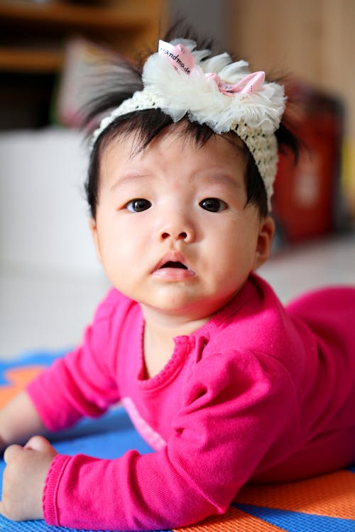 Free Selective Focus Photo of a Cute Baby with a White Headband Looking at the Camera Stock Photo