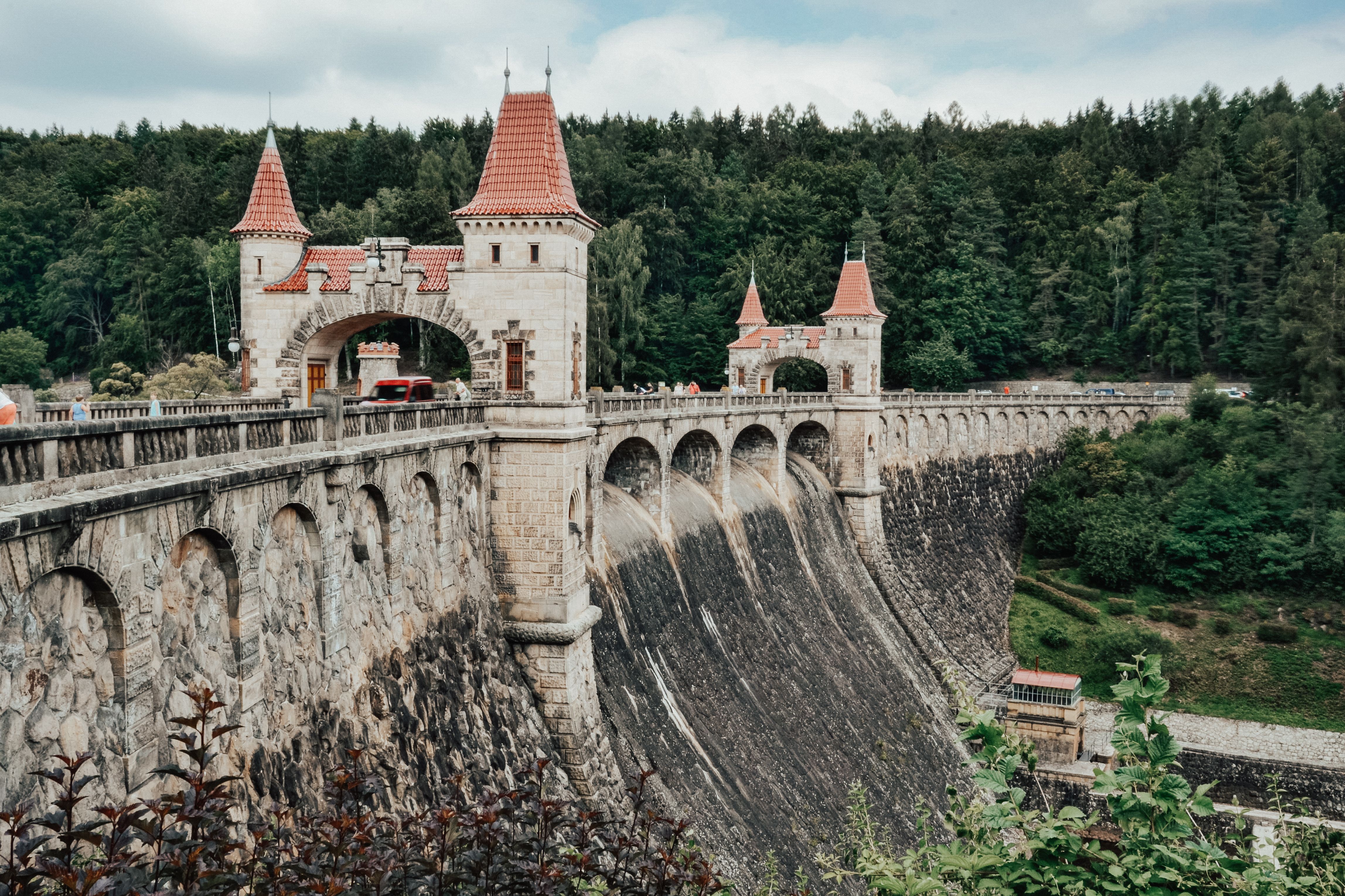 Picturesque Les Království Dam featuring medieval architecture surrounded by lush greenery.
