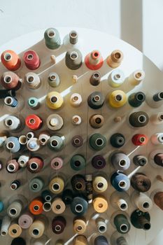 A vibrant assortment of sewing threads neatly organized in a workshop setting, bathed in natural light.
