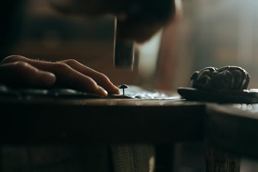 Close-up of a skilled hand restoring antique furniture using a hammer and nail.