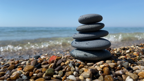 Free Balanced stones on a pebble beach with a calm ocean in the background. Stock Photo