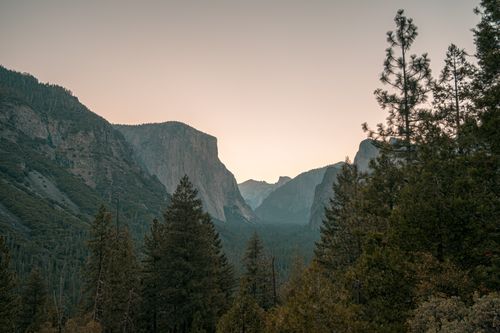 Free A breathtaking view of Yosemite Valley with towering cliffs and lush trees at dusk, offering a serene natural landscape. Stock Photo