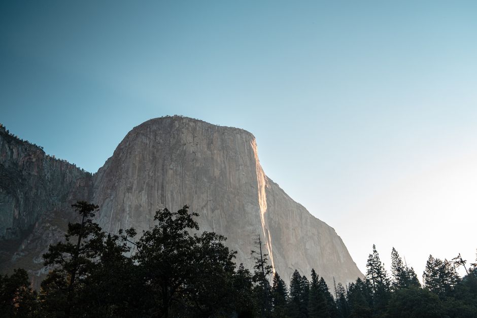 Breathtaking view of El Capitan in Yosemite Valley with a clear sky and lush greenery.
