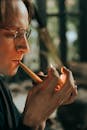 室内，一个戴着眼镜的男人专注地点燃烟斗，特写肖像