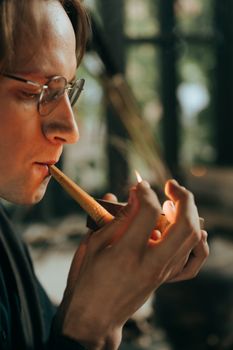 室内，一个戴着眼镜的男人专注地点燃烟斗，特写肖像