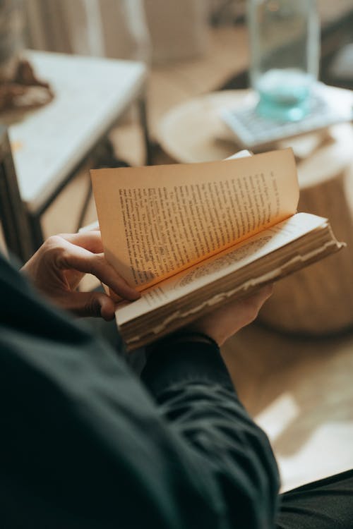 Person Holding Book on Table