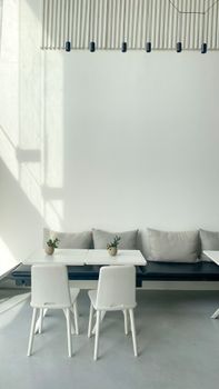 Bright minimalist interior featuring white chairs and tables with soft cushions.