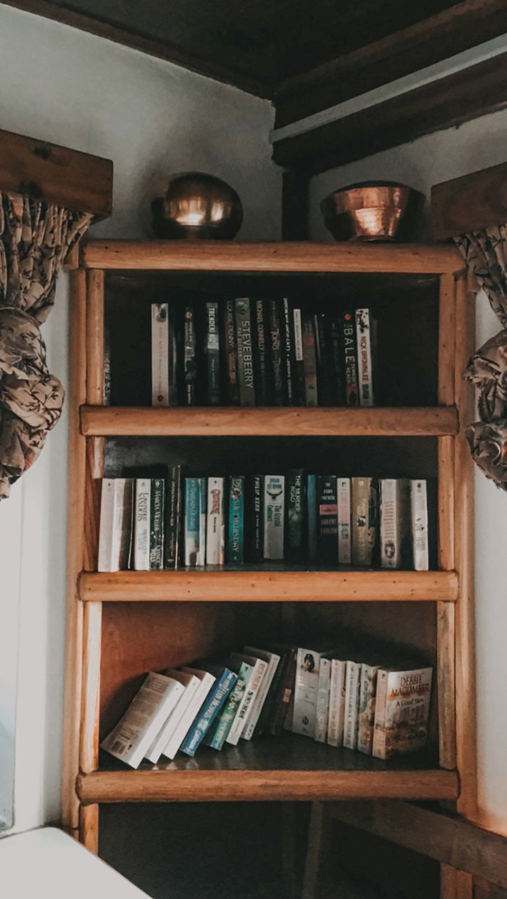 A wooden bookshelf filled with books and adorned with copper accents, creating a cozy atmosphere.