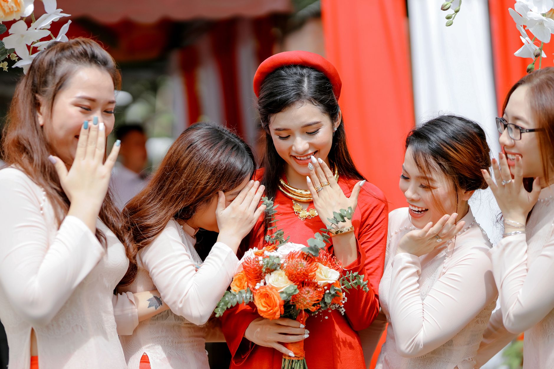 Positive young bride standing with friends and smiling while looking at hands on wedding day