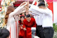 Positive newlyweds in elegant traditional apparels passing wedding rite with friends in decorated yard