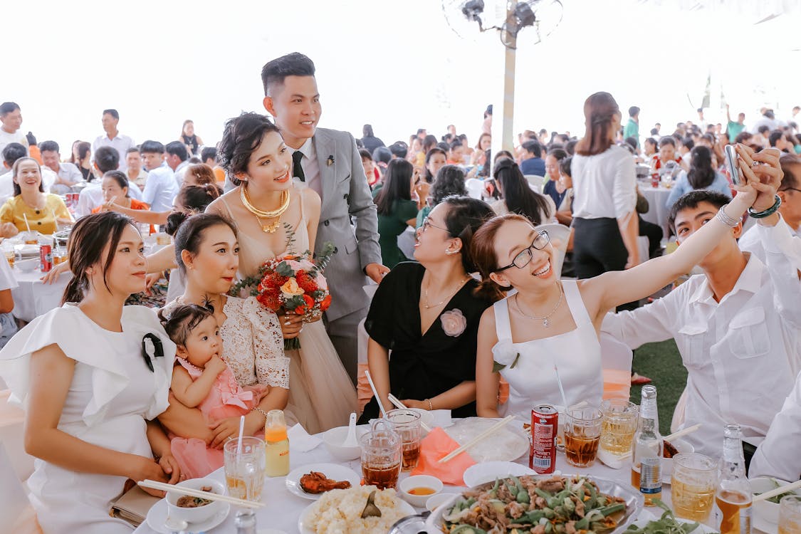 Free Group of happy friends in elegant clothes taking selfie with newlyweds on wedding party Stock Photo