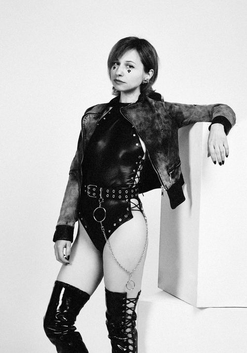 Free Black and white of serious extravagant female model wearing provocative clothes looking at camera leaning on cube in studio Stock Photo