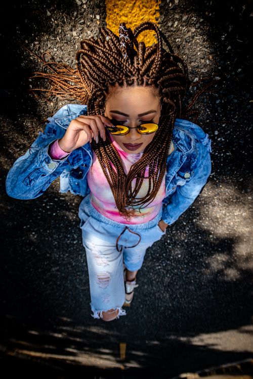 Free Trendy woman in colorful outfit showcasing urban street fashion with braided hair. Stock Photo