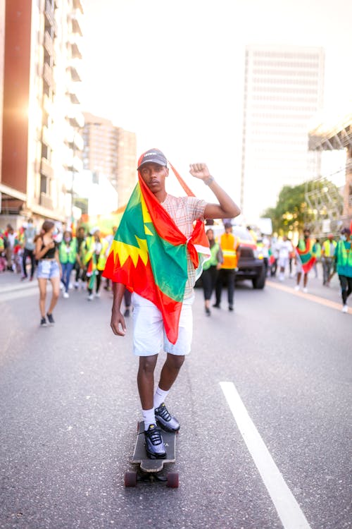 A Man Riding His Skateboard with a Flag Tied Around His Body