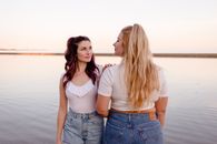 Positive females standing on seashore in summer day