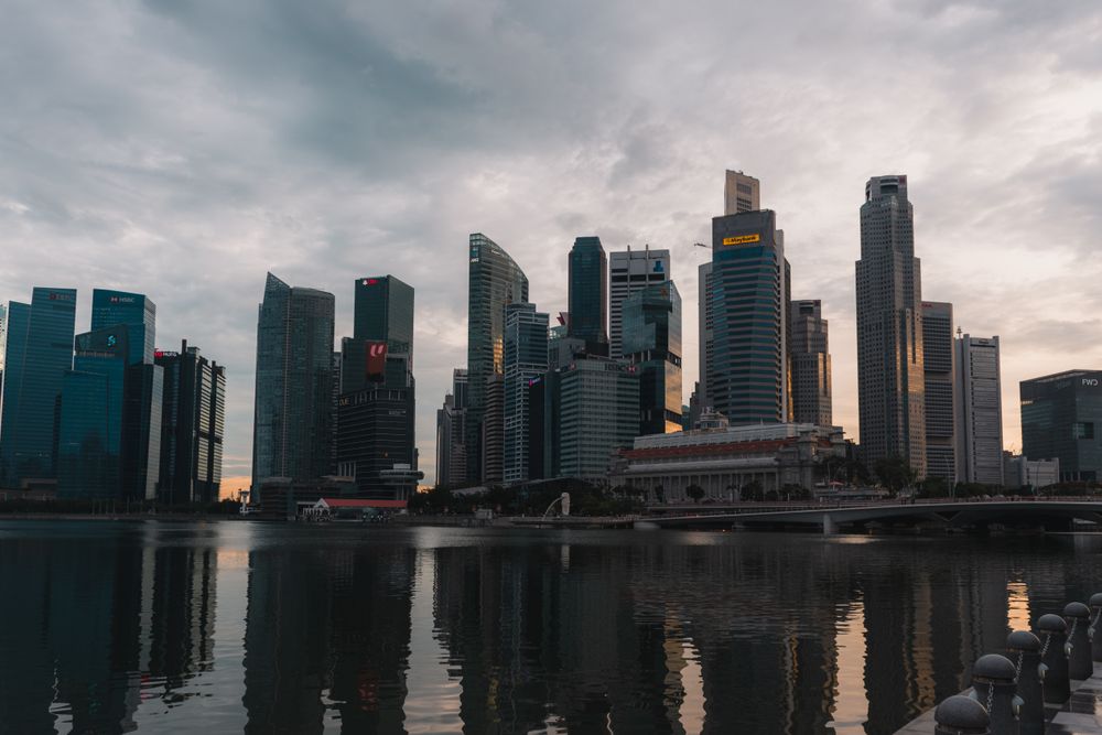 Dramatic skyline of Singapore reflecting on waterfront at dusk with towering skyscrapers.