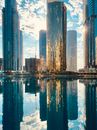 平静的湖泊倒映着令人惊叹的城市景观与摩天大楼，映衬在明亮的蓝天下