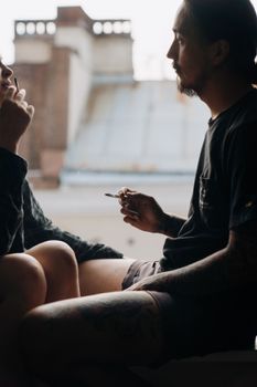 一对夫妇坐在窗台旁，在室内一起吸烟，共享片刻时光