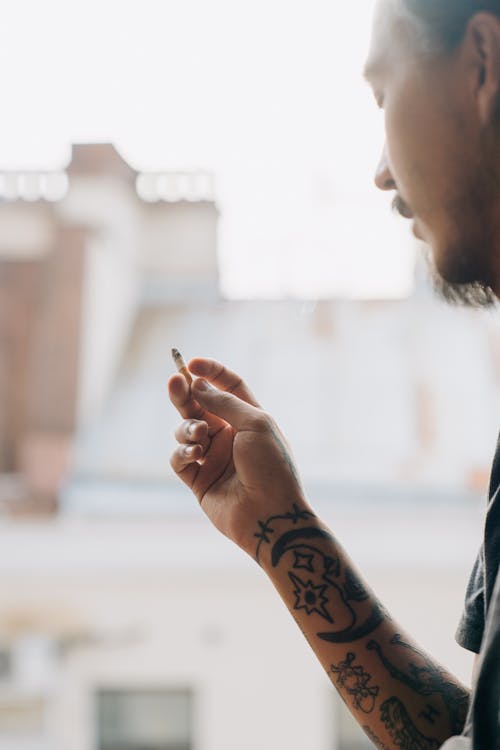 Crop Ethnique Hipster Man Smoking Cigarette Sur Balcon