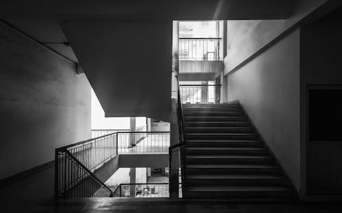 Grayscale Photo of Staircase in Building