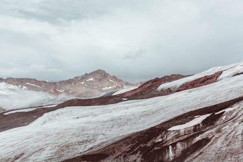 Snowy mountain slope under cloudy sky