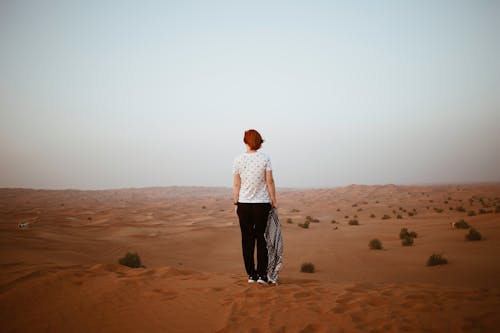 Unrecognizable woman in endless desert in overcast