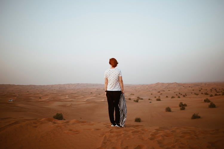 Unrecognizable Woman In Endless Desert In Overcast