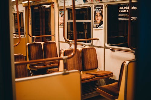 Interior of empty subway train with metal railing and seats near big windows