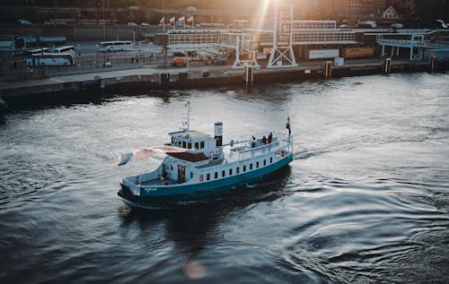 From above of contemporary sailing ship on calm rippled water near city port at sunset