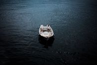 一艘孤独的船静静地漂浮在平静的水面上，营造出一种宁静而隔绝的氛围