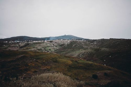 Free Picturesque view of hills with green grass and plants under cloudy sky in overcast weather Stock Photo