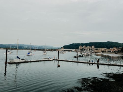 Free Different small boats in seaport near mountains in valley under grey cloudless sky in daylight Stock Photo