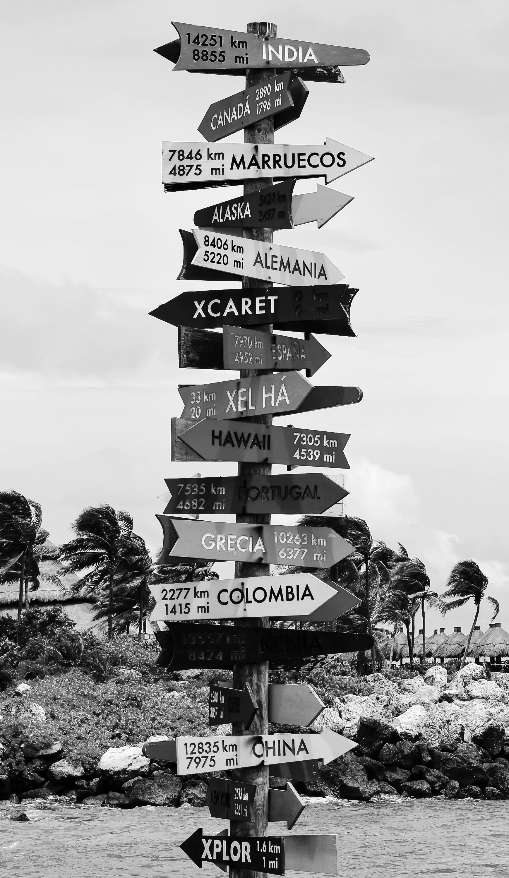 Black-and-white signpost showing distances to various global destinations in Quintana Roo.
