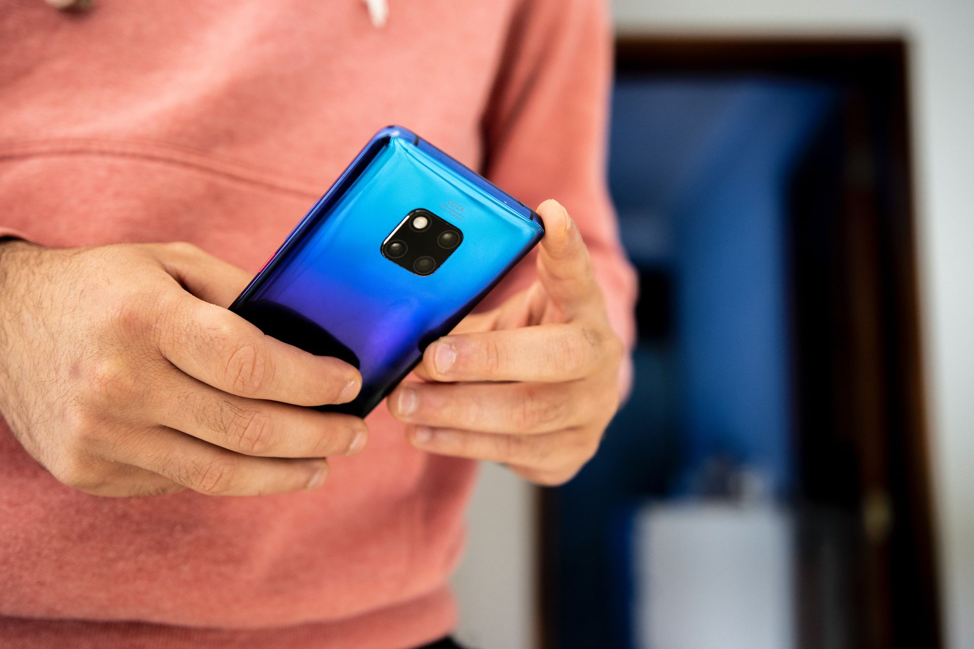 Close-up image of a person using a vibrant blue smartphone indoors.