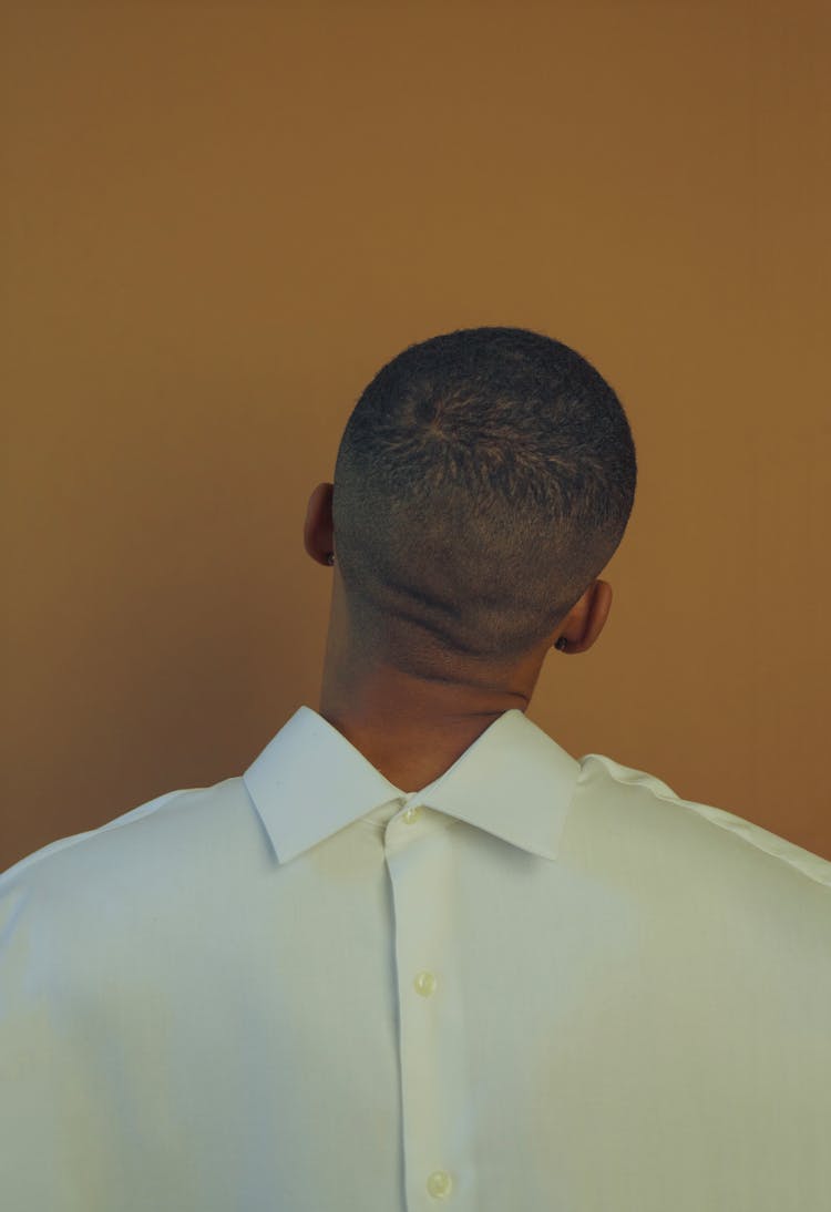 Black Man In White Shirt Standing Behind Wall