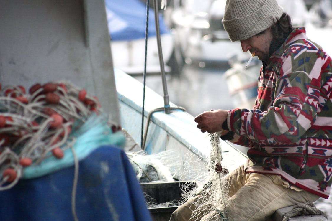 A Man Holding a Fish Net on a Boat · Free Stock Photo