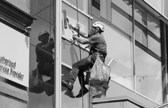 Male worker washing glass facade of building