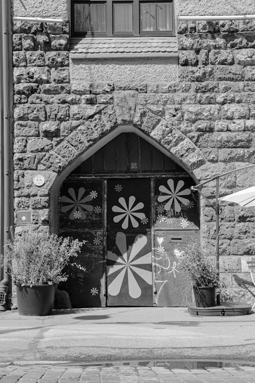Black and white of aged masonry house with weathered wall and entrance painted with flowers