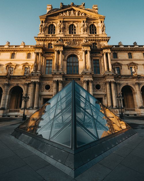 Free Stunning view of the Louvre Museum and its iconic glass pyramid in golden light. Stock Photo