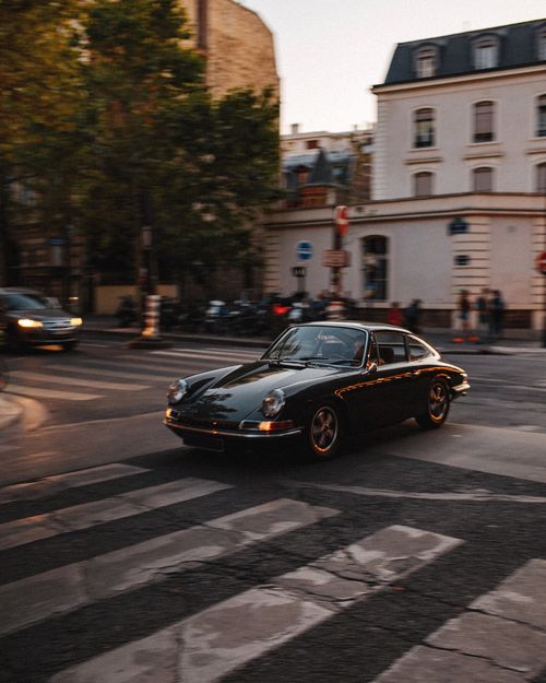 Free Vintage car driving through a European street, evoking a sense of nostalgia and classic elegance. Stock Photo