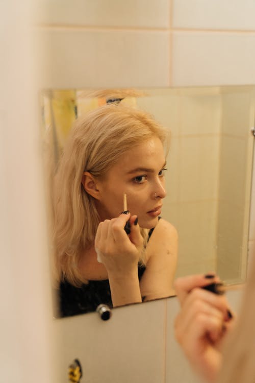 Een Vrouw Die In De Spiegel Kijkt Terwijl Ze Make Up Op Haar Gezicht Aanbrengt