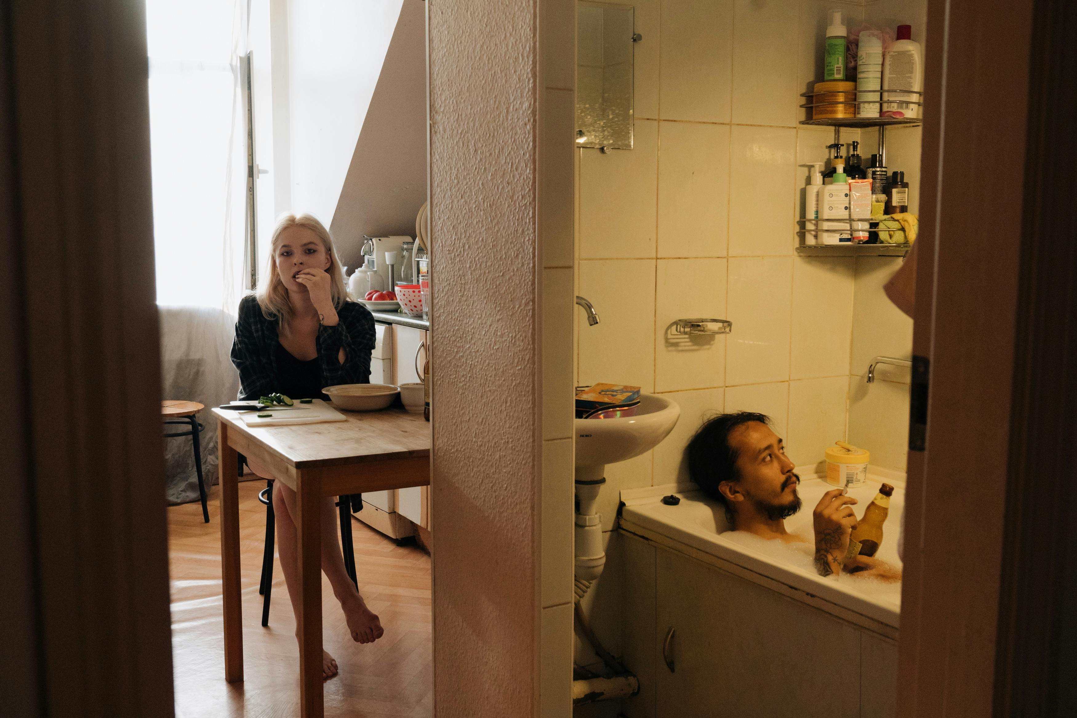 一个亲密的家庭时刻展现了一对夫妇在舒适公寓中的生活：一个在厨房，另一个在浴缸里