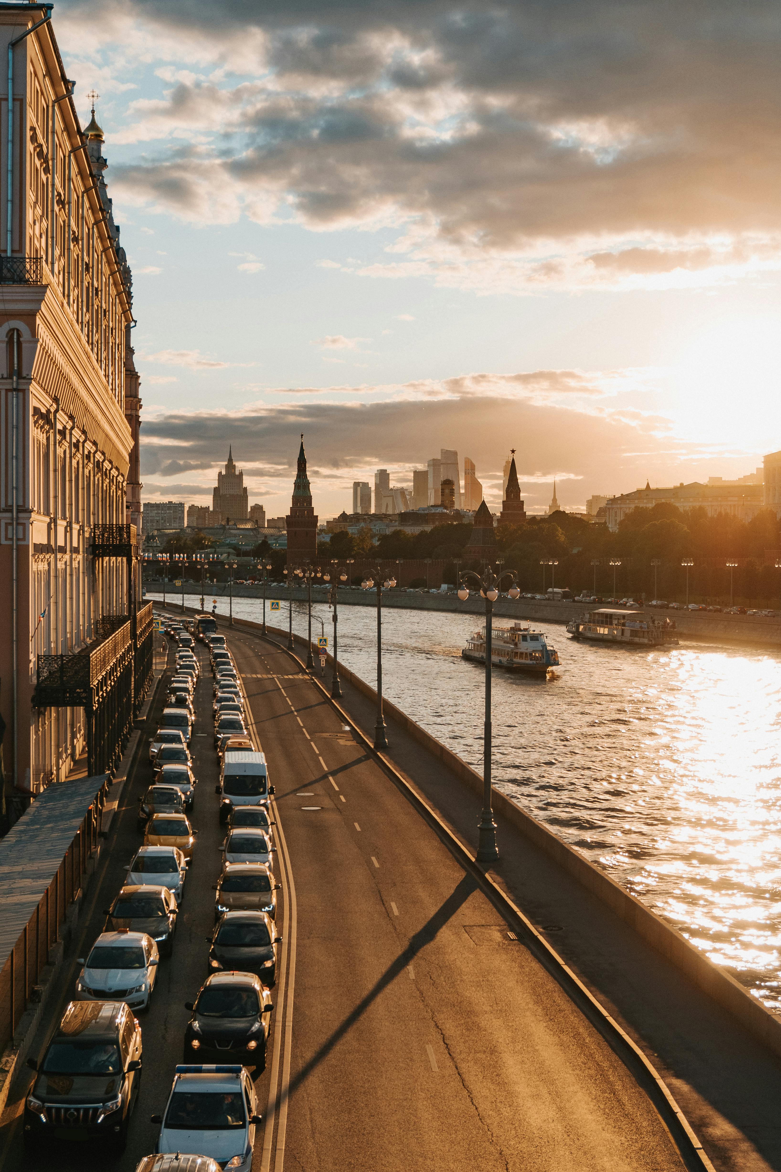 日落时分，从莫斯科河滨俯瞰，汽车、天际线与水中倒影构成一幅迷人画卷