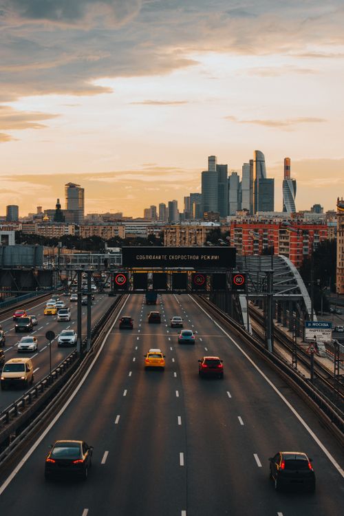 Free Aerial view of a city highway with cars during sunset, featuring modern skyscrapers in the background. Stock Photo