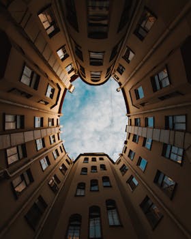 Low-angle view of a building's courtyard with a cloudy sky.