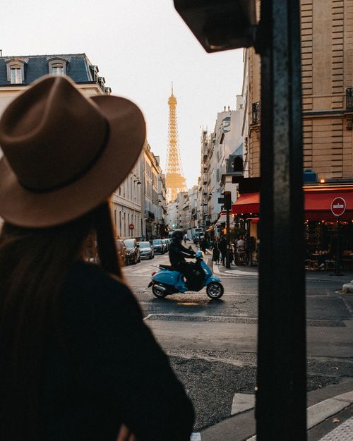 Free View of Eiffel Tower from a Paris street with a scooter and pedestrian. Stock Photo